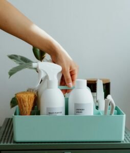 Hand arranging cleaning products in a tidy organizer, promoting cleanliness and order.